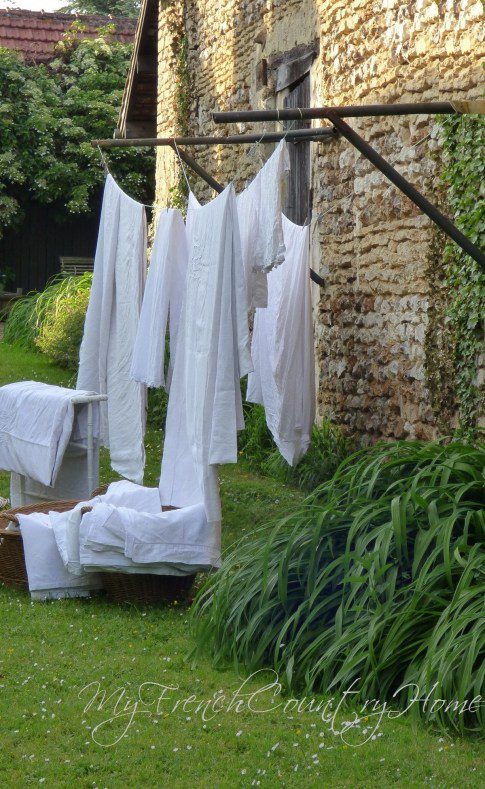 several linen sheets hanging from a washing line outdoors