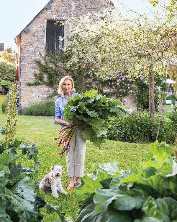 woman in garden holding a bushel of leafy vegetables