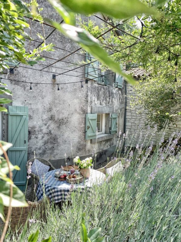 stone wall of country house with blue shutters and an outdoor tablescape