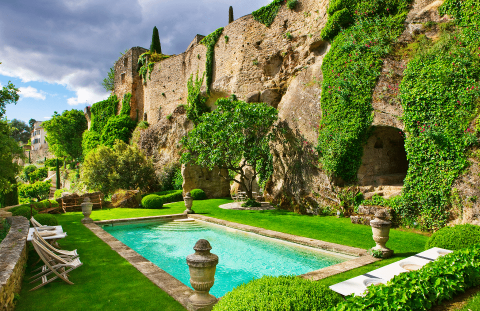 a wall with foliage and a bright blue pool beneath
