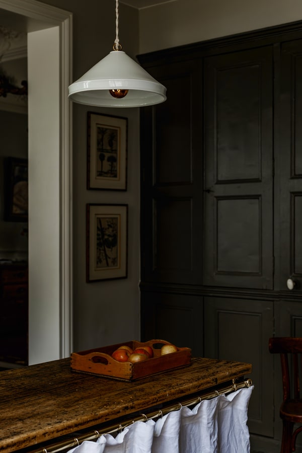 White pendant light in front of two antique French paintings - French Kitchen Design Inspiration